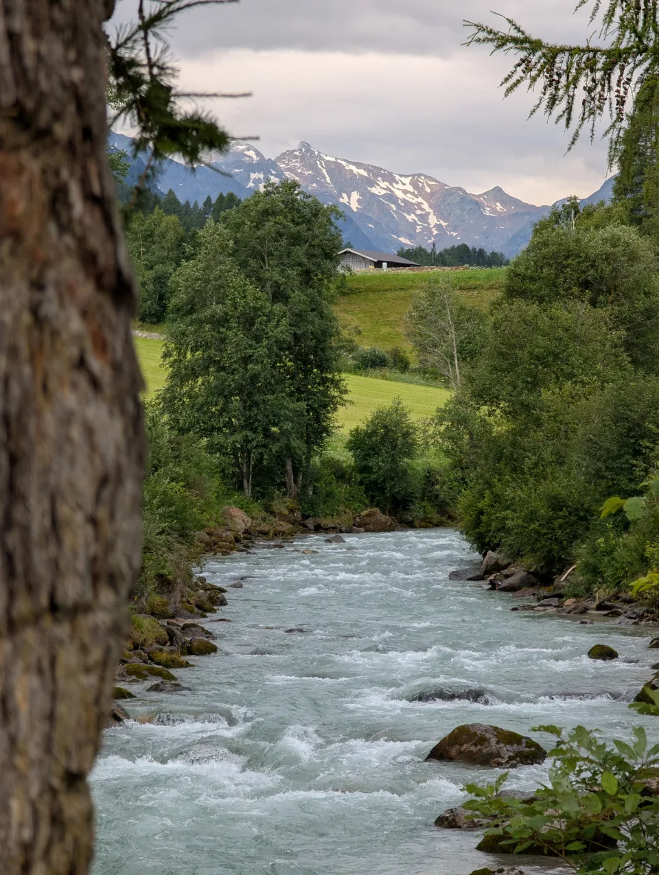 Mountain stream with snow-covered massif and an alp house