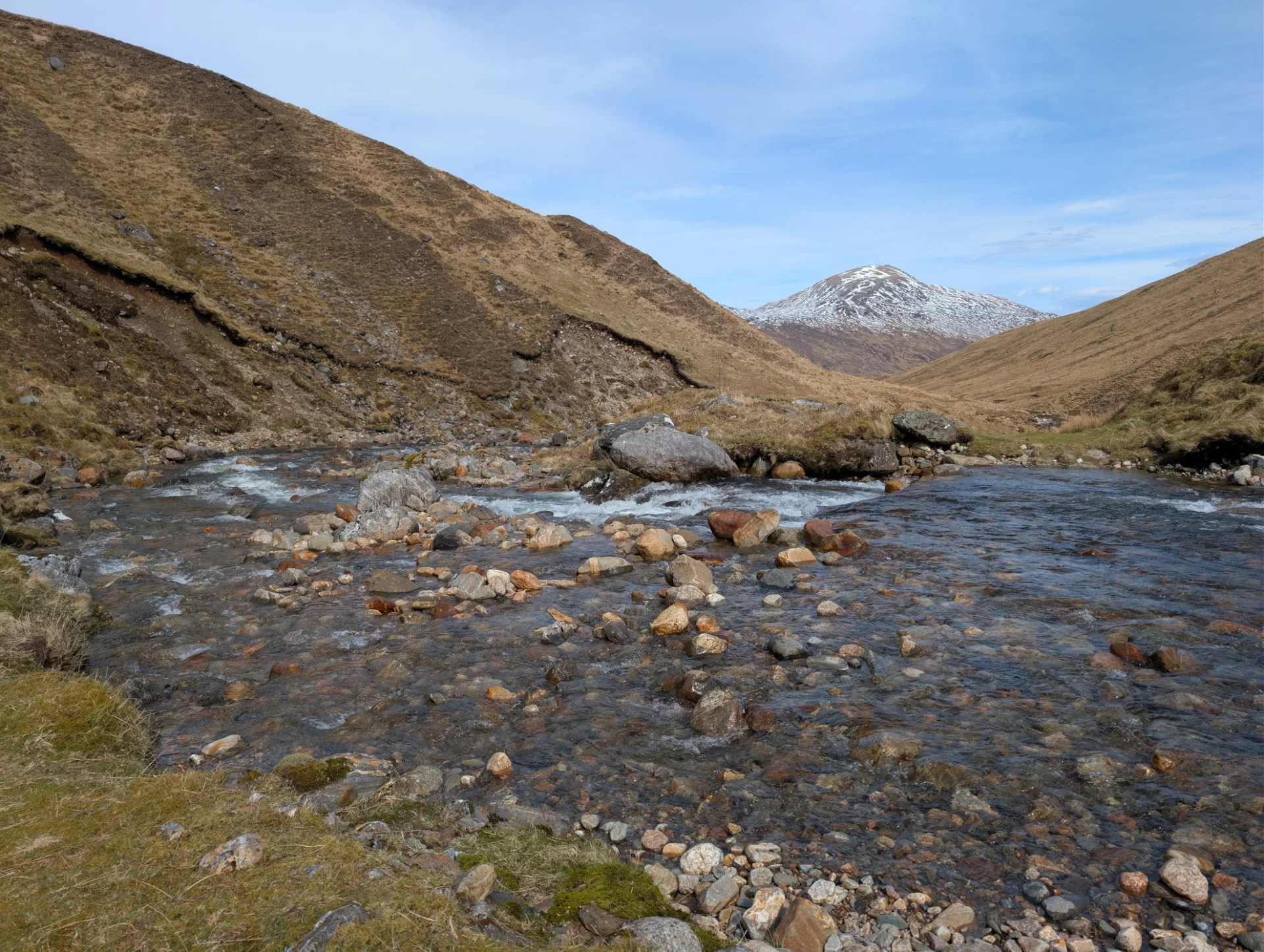 Rocky burn with a snow-covered mountain behind