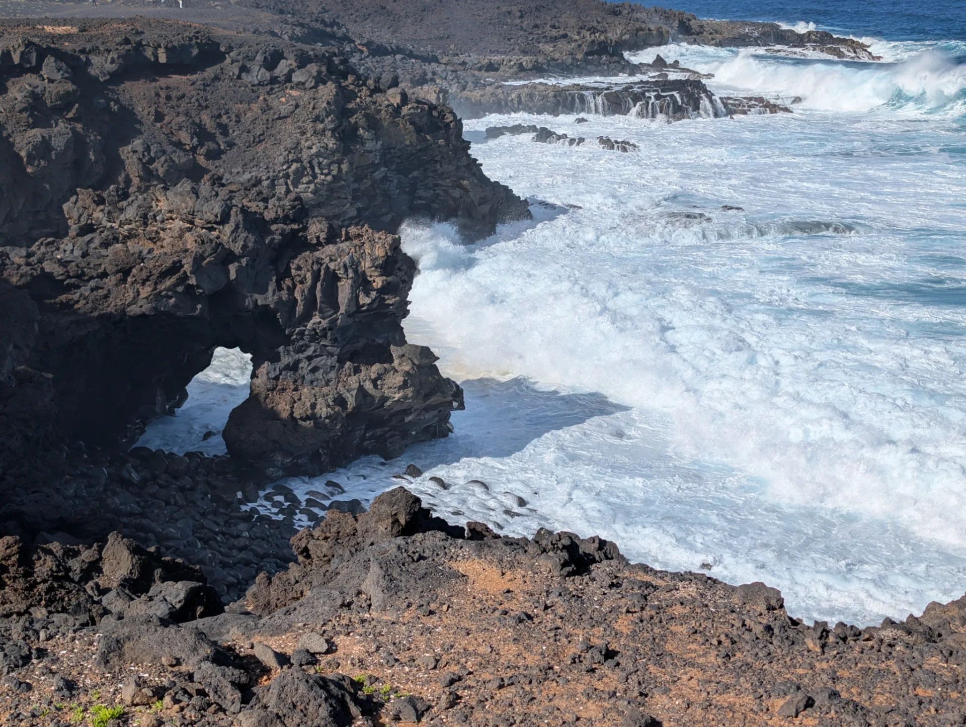 A lava arch on the coast, carved out by the surf.