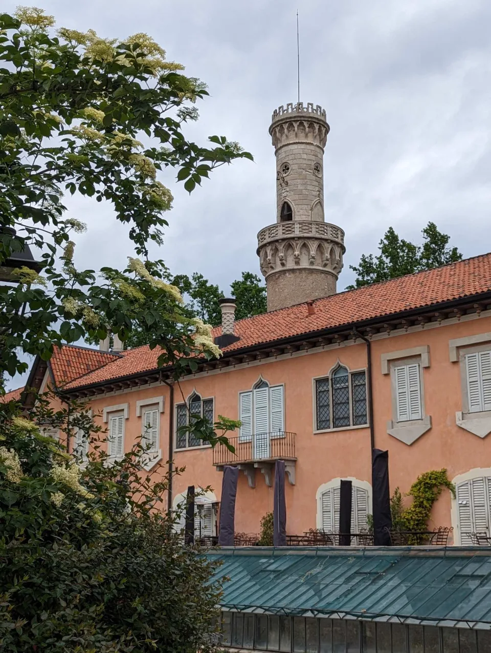 A neo-Gothic round tower above a villa at the edge of the gardens