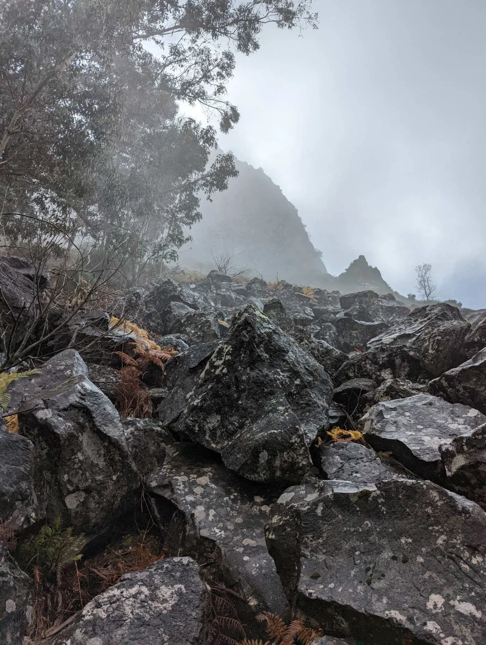 A mist-shrouded rocky peak above a boulder field
