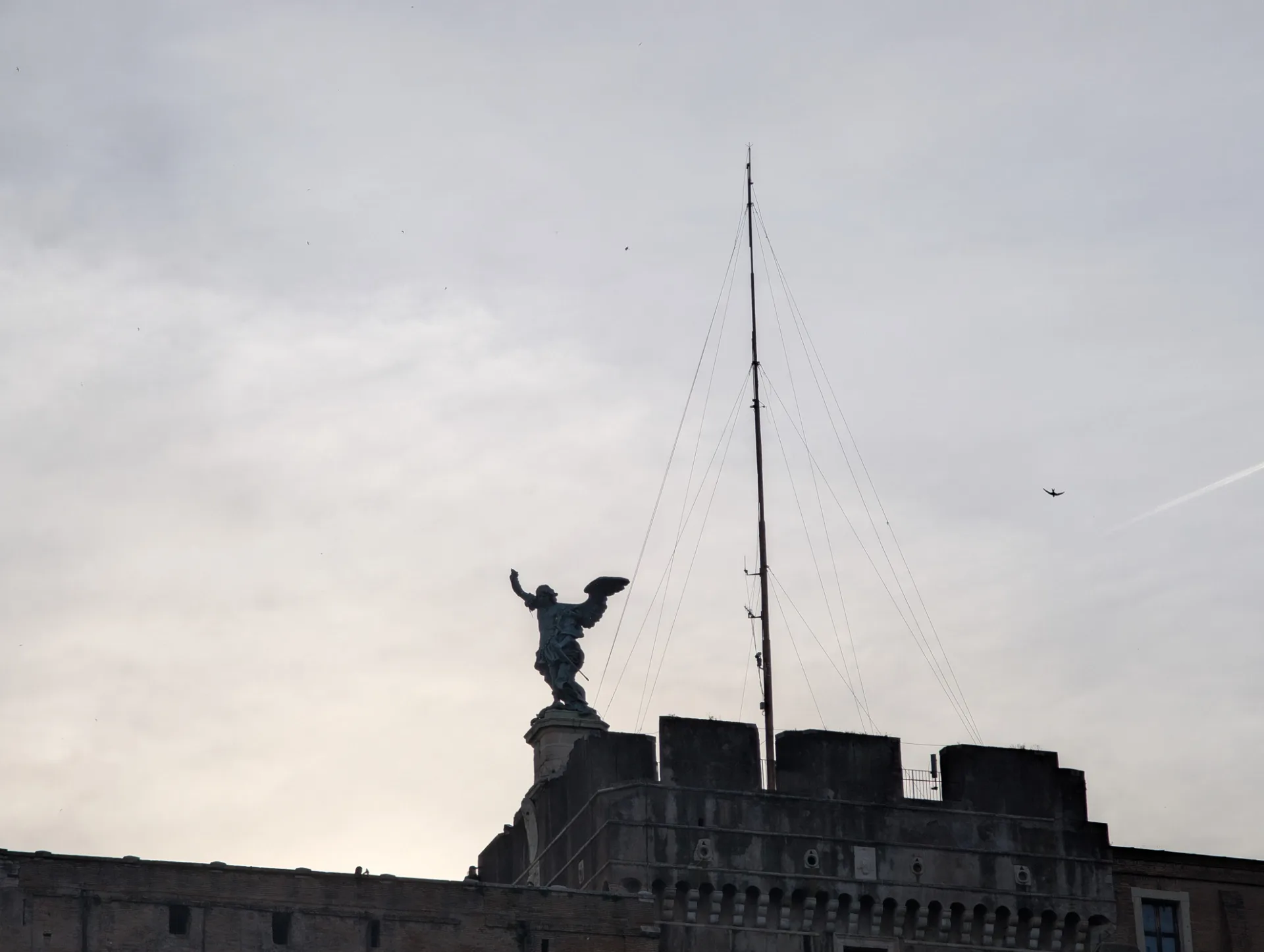 Angel statue atop Castel Sant'Angelo — silhouette against a grey sky