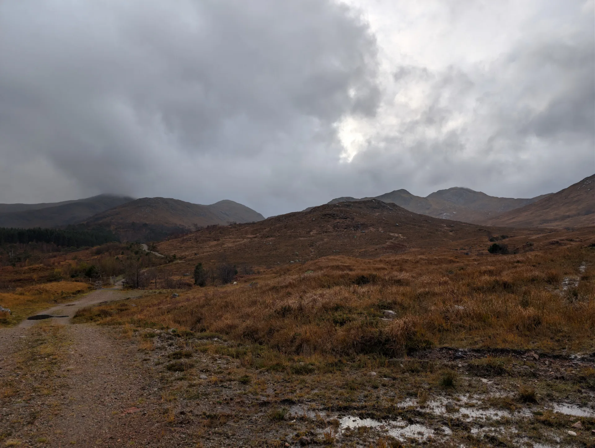 Highland track under dramatic clouds — a brief break of light over the ridges